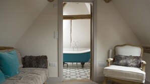 A bedroom with a bed, a chair, and a view into a bathroom with a bathtub. - The Greyhound Inn (Wantage)