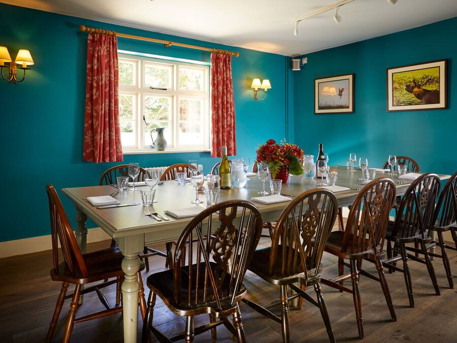 Een eetkamer met een tafel voor zes personen, omringd door houten stoelen, met een raam en gordijnen aan de muur.