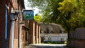 A narrow street with a pub named "The Greyhound" and a traditional half-timbered house. - The Greyhound Inn (Wantage)