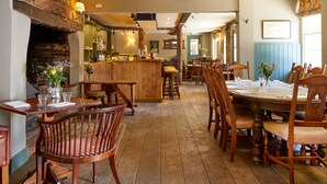 A cozy restaurant with wooden furniture, a brick fireplace, and a bar area. - The Greyhound Inn (Wantage)