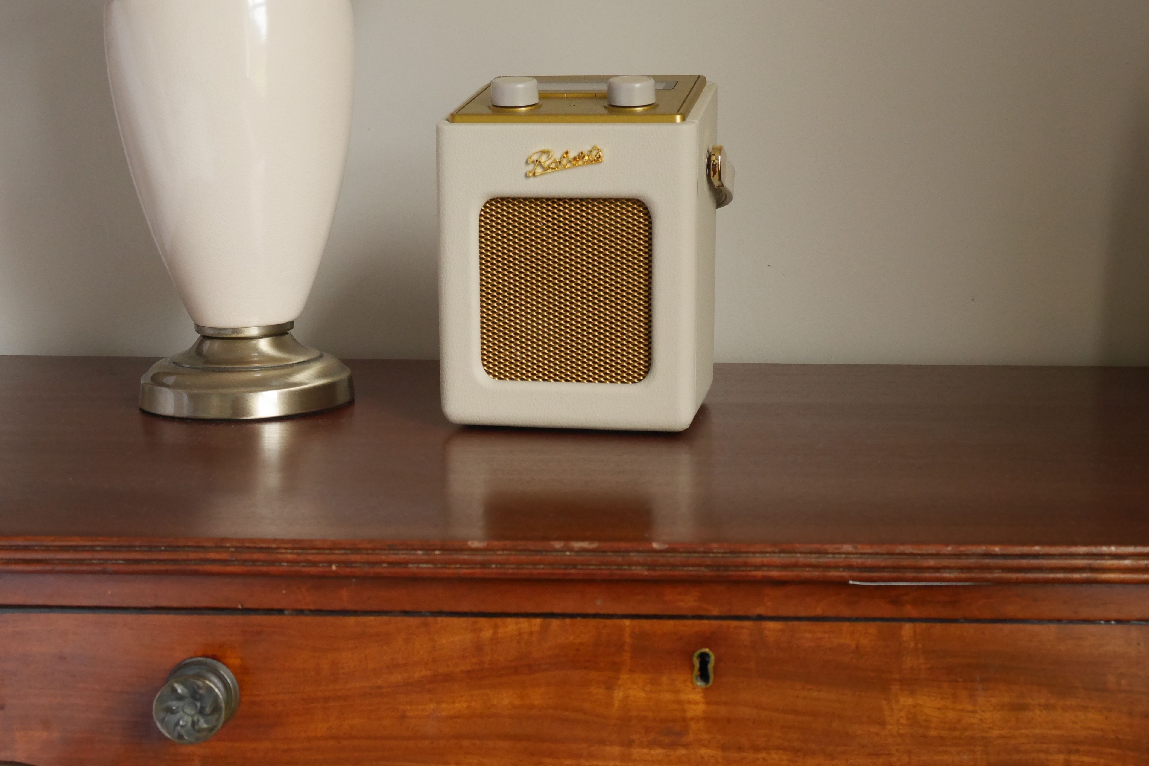 A vintage radio and a vase on a wooden dresser.