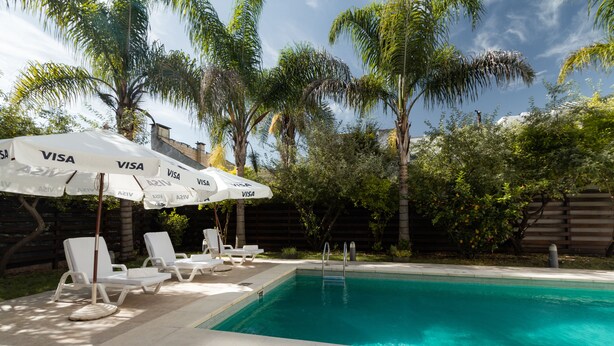 A swimming pool with lounge chairs and umbrellas, surrounded by palm trees and a wooden fence. - Gran Hotel Brisas del Hum (Mercedes)