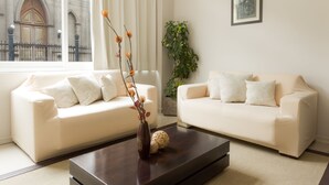 A modern living room with two white sofas, a dark wooden coffee table, a vase with dried flowers, and a framed picture on the wall. - Gran Hotel Brisas del Hum (Mercedes)