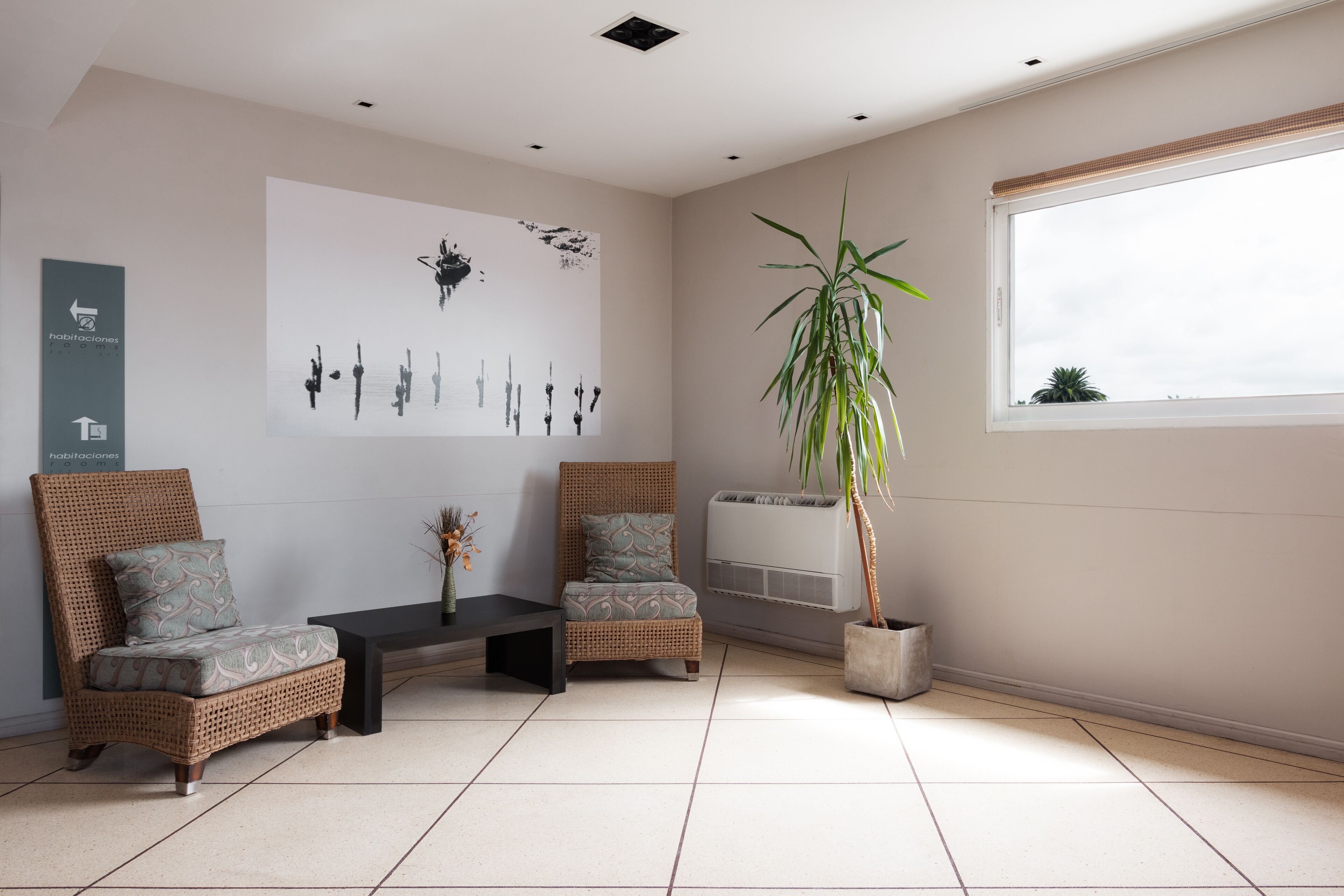 A modern living room with two wicker sofas, a coffee table, and a large window.