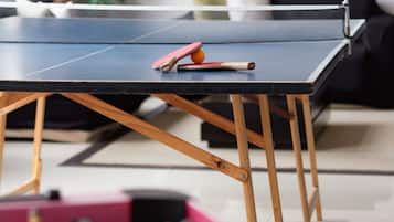 A foosball table in a room with a black sofa and a plant in the background.