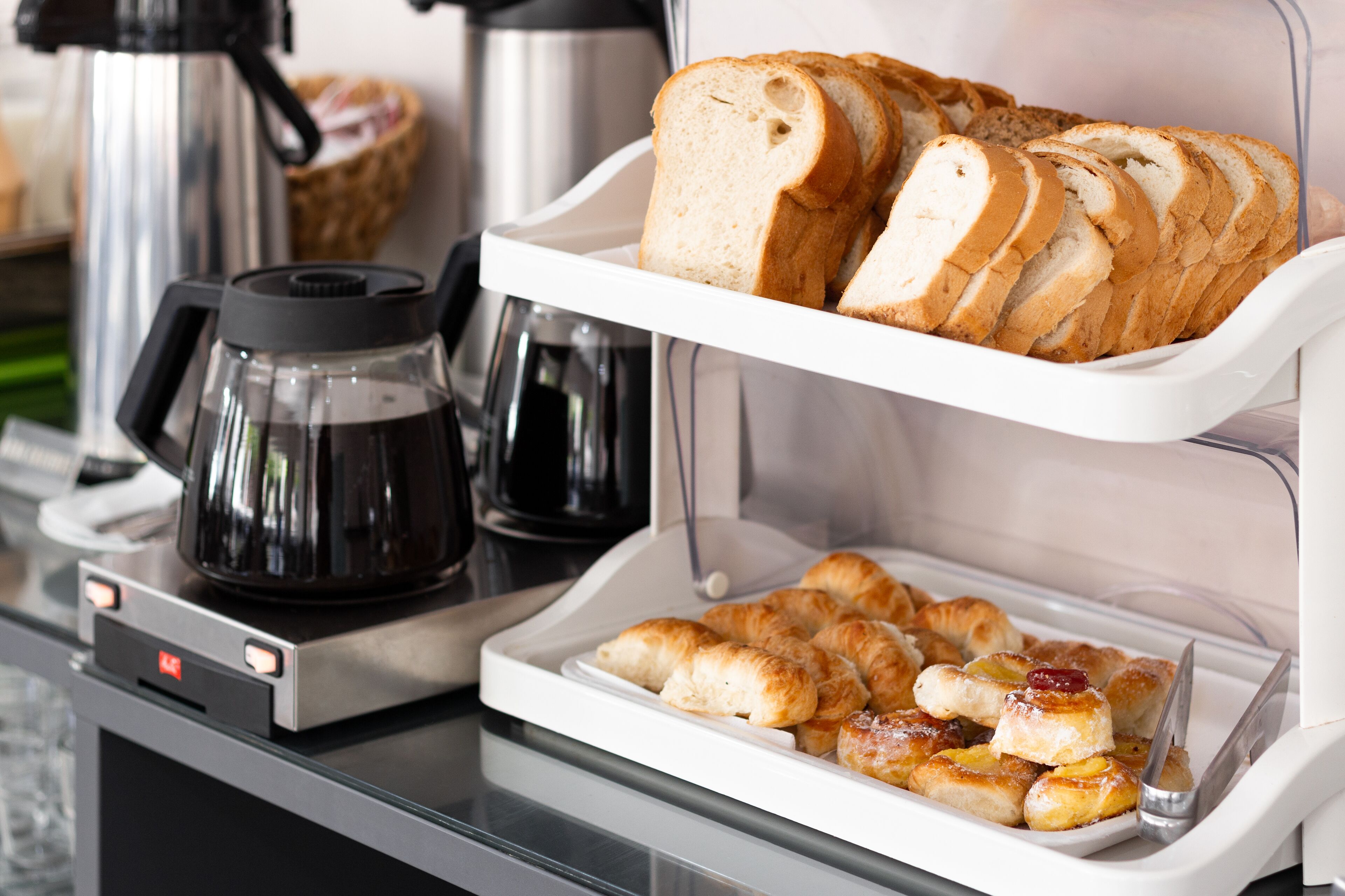 A breakfast buffet with sliced bread and pastries.