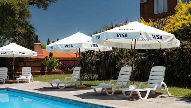 A pool area with lounge chairs and umbrellas labeled "VISA". - Gran Hotel Fray Bentos (Fray Bentos)