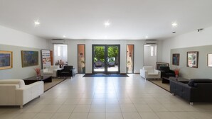 A spacious lobby with a modern design, featuring a central seating area with sofas and armchairs, a reception desk, and framed artwork on the walls. - Gran Hotel Fray Bentos (Fray Bentos)