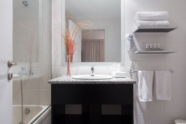 A modern bathroom with a glass shower enclosure, a sink with a marble countertop, and a mirror above the sink.