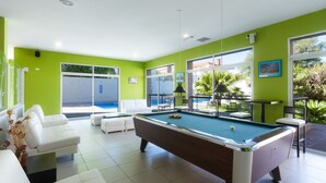 A pool room with a pool table, white sofas, and a view of the outside. - Gran Hotel Fray Bentos (Fray Bentos)