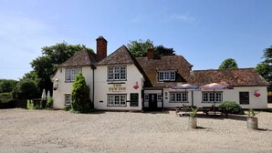 A traditional pub named 'The New Inn' with a gravel driveway, outdoor seating, and a clear blue sky. - The New Inn - Kidmore End (Reading)