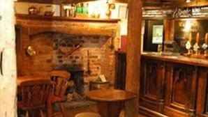A cozy bar area with wooden furniture, a brick wall, and a counter with bottles. - The New Inn - Kidmore End (Reading)