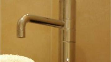 A bathroom with a modern faucet and a towel hanging on the wall.