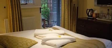A hotel room with a bed, a nightstand, a TV, and a view of the outdoors.