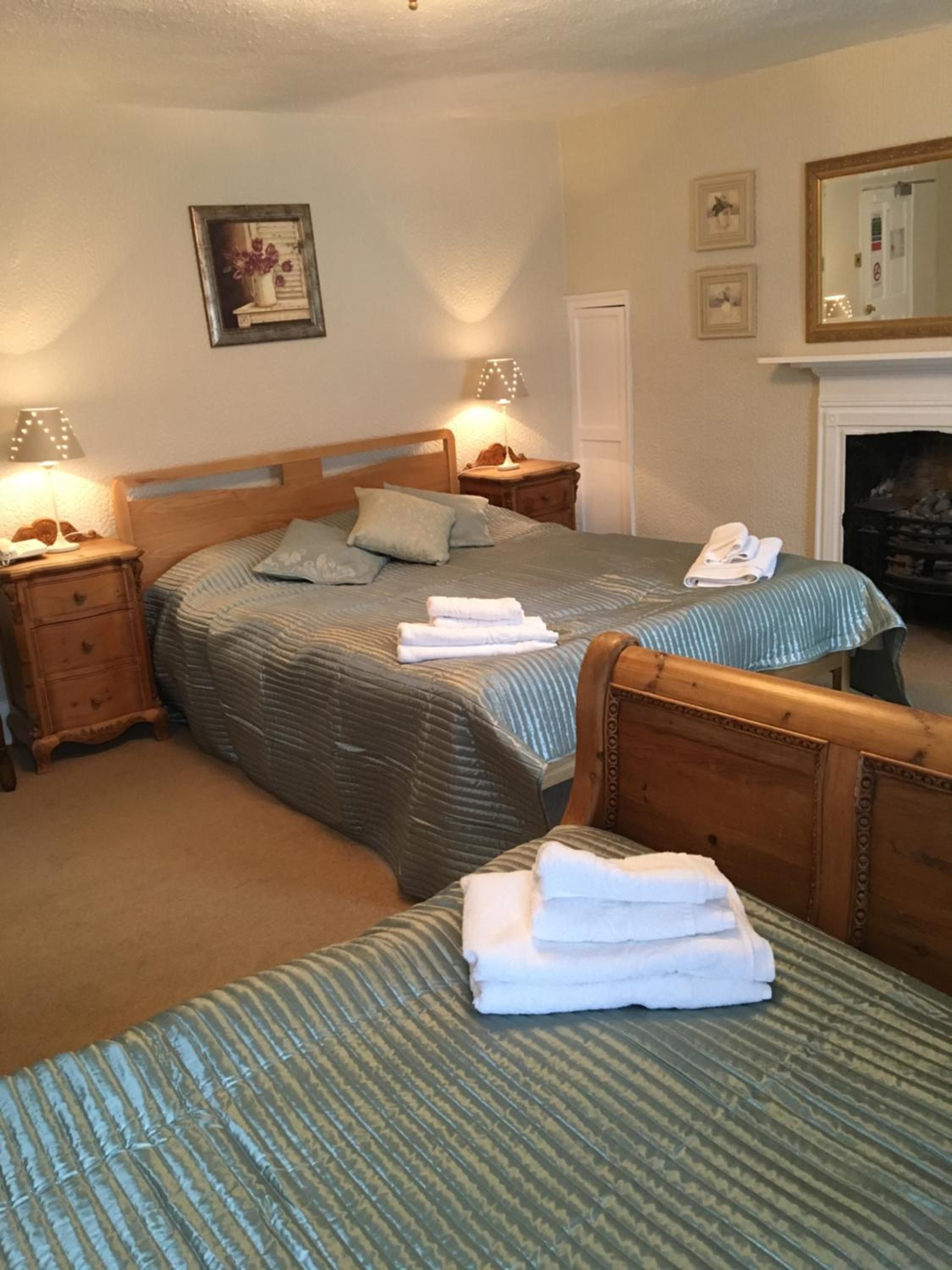 A hotel room with two beds, a fireplace, and a mirror on the wall.