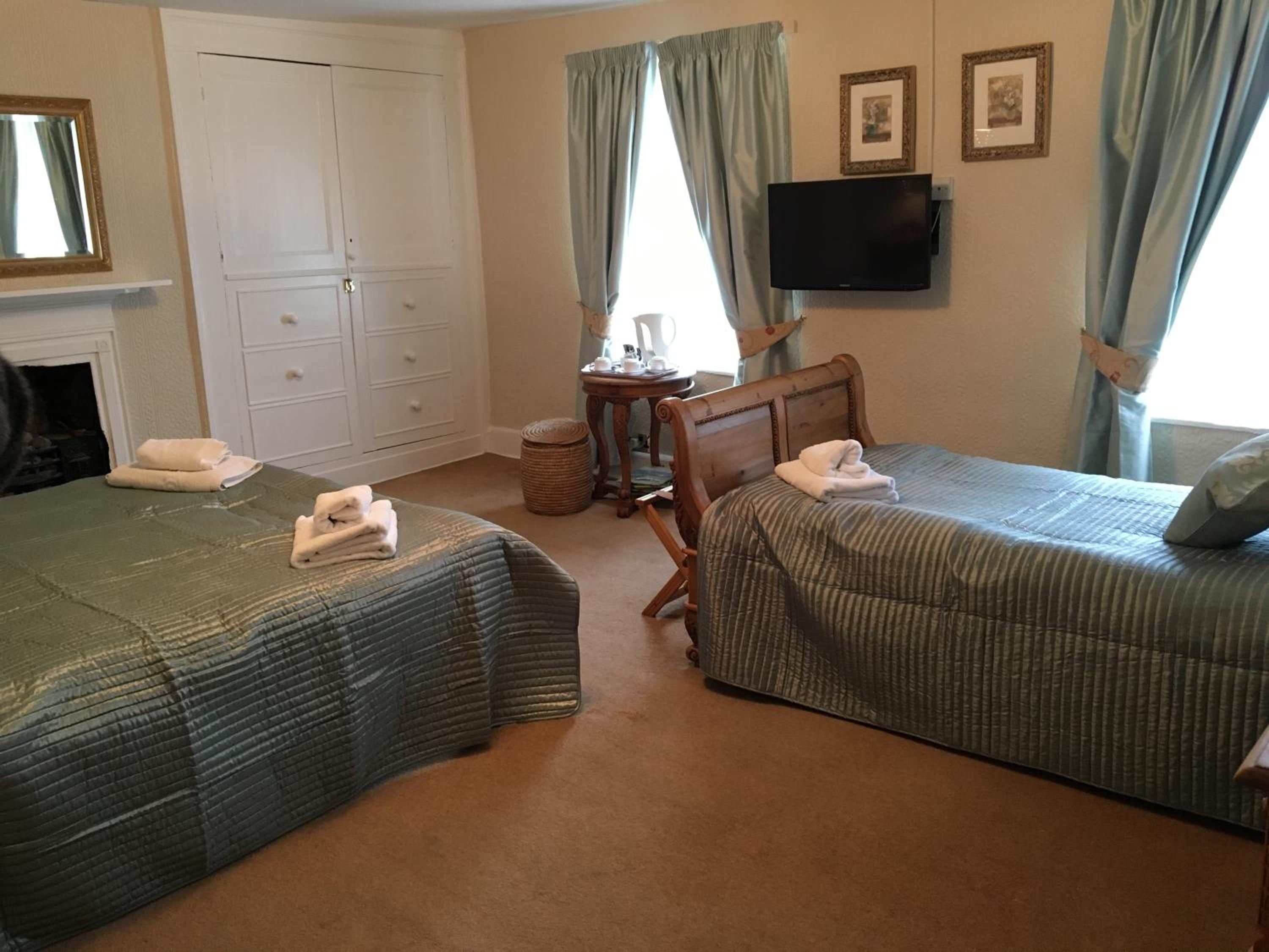 A hotel room with two beds, a television, a small table, and a wardrobe.