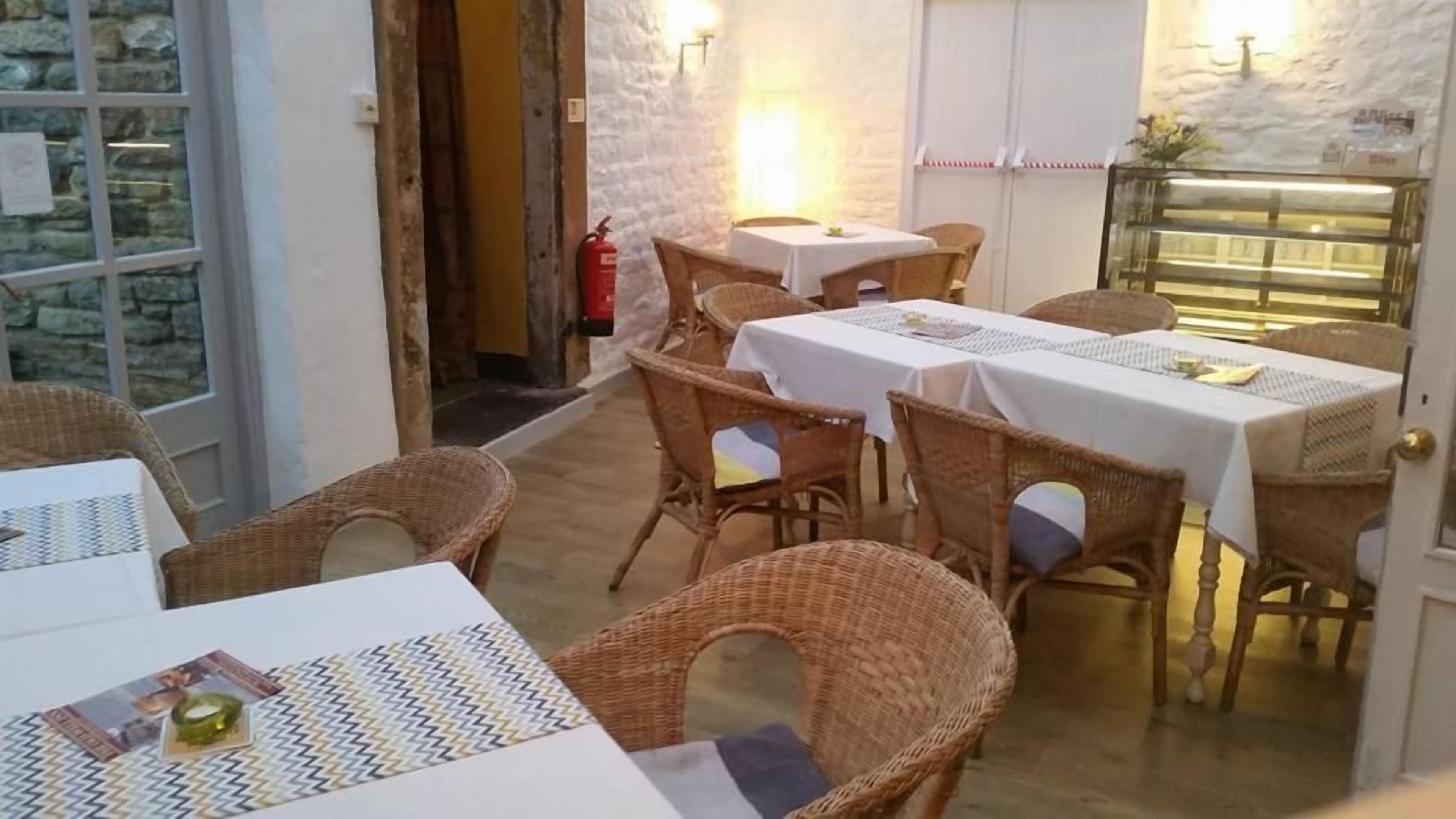 Un espacio de comedor al aire libre con mobiliario de mimbre y manteles blancos.