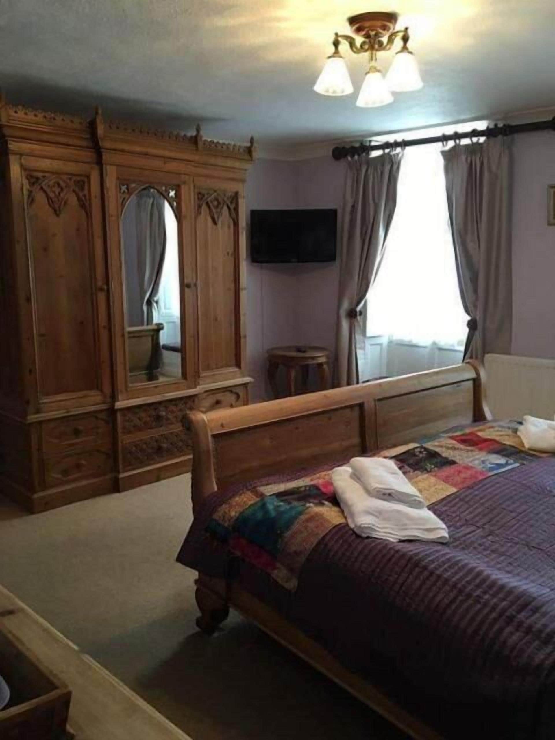 A bedroom with a wooden bed, a television, and a wardrobe.