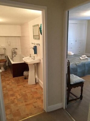 A bathroom with a toilet, sink, and bathtub. There is a mirror above the sink and a towel on the floor.