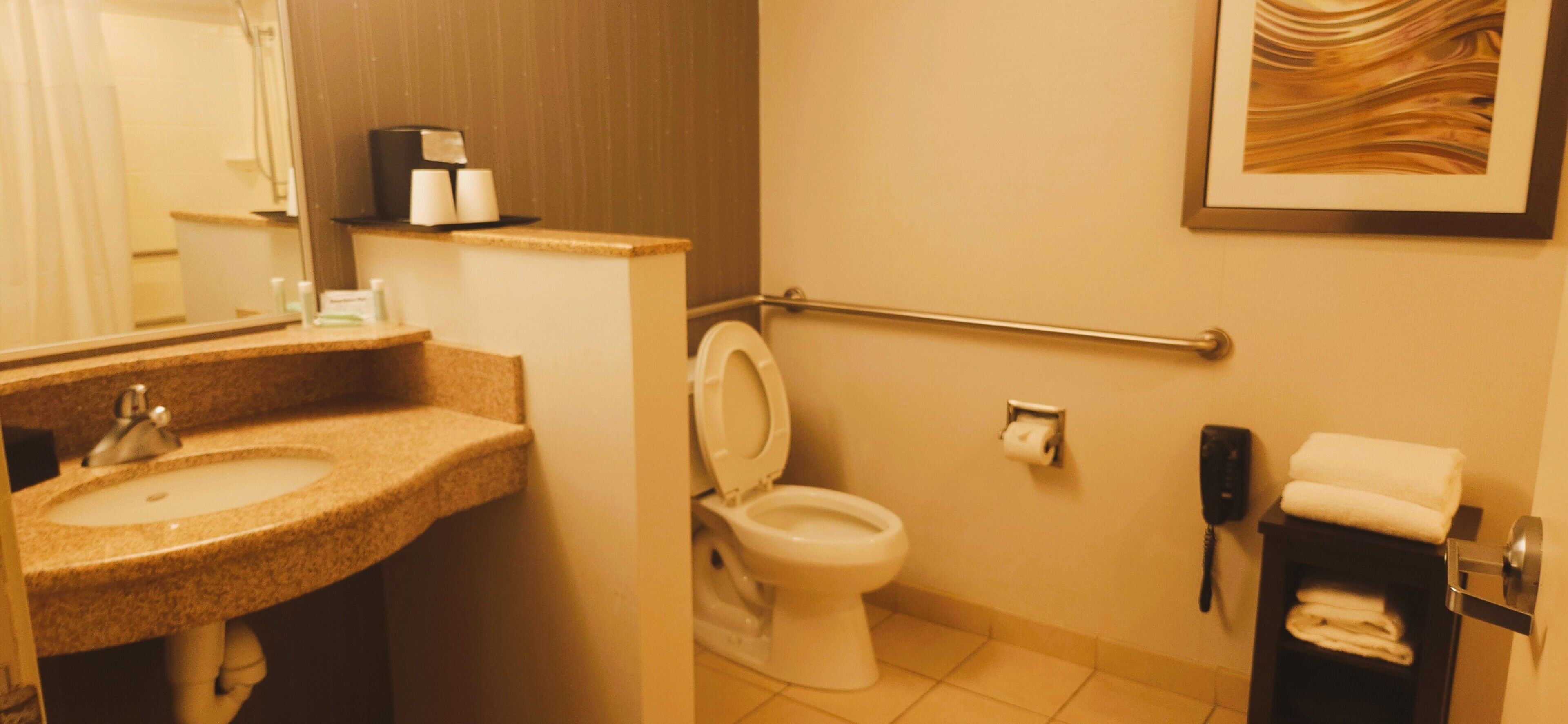 Un baño con lavamanos, inodoro, secador de manos y perchero para toallas.