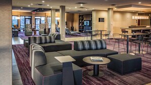 A modern lobby with seating areas, a bar, and a television.