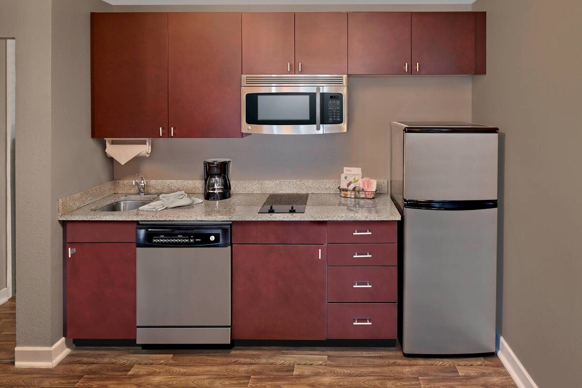 Una cocina moderna con electrodomésticos de acero inoxidable, incluyendo un microondas y un refrigerador, y armarios de madera.