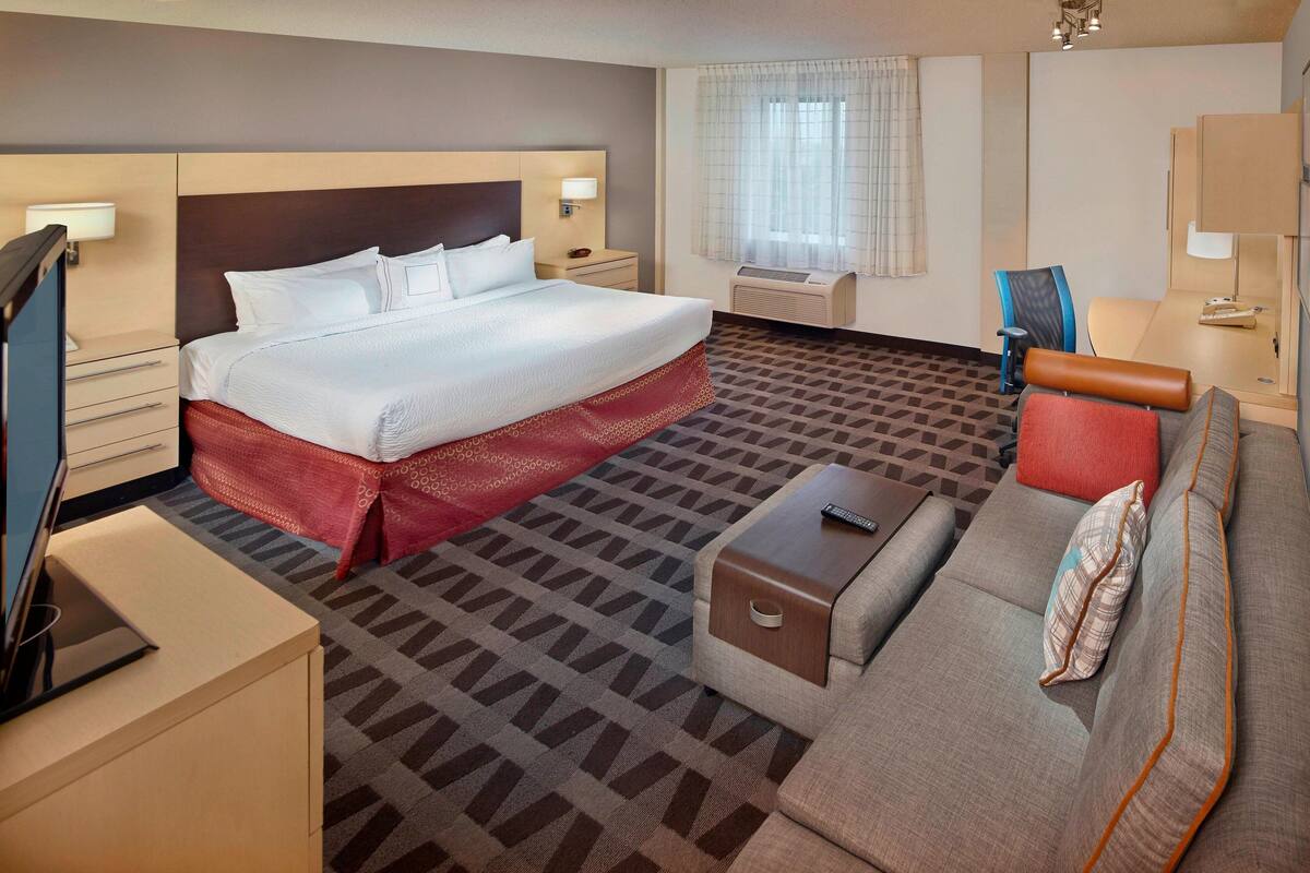 Una habitación de hotel con una cama grande, un sofá, un televisor y un escritorio.