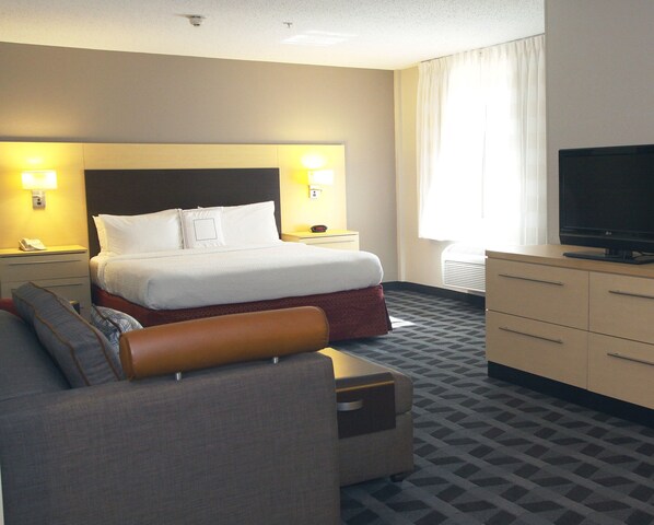 A hotel room with a bed, a TV, a desk, and a couch.