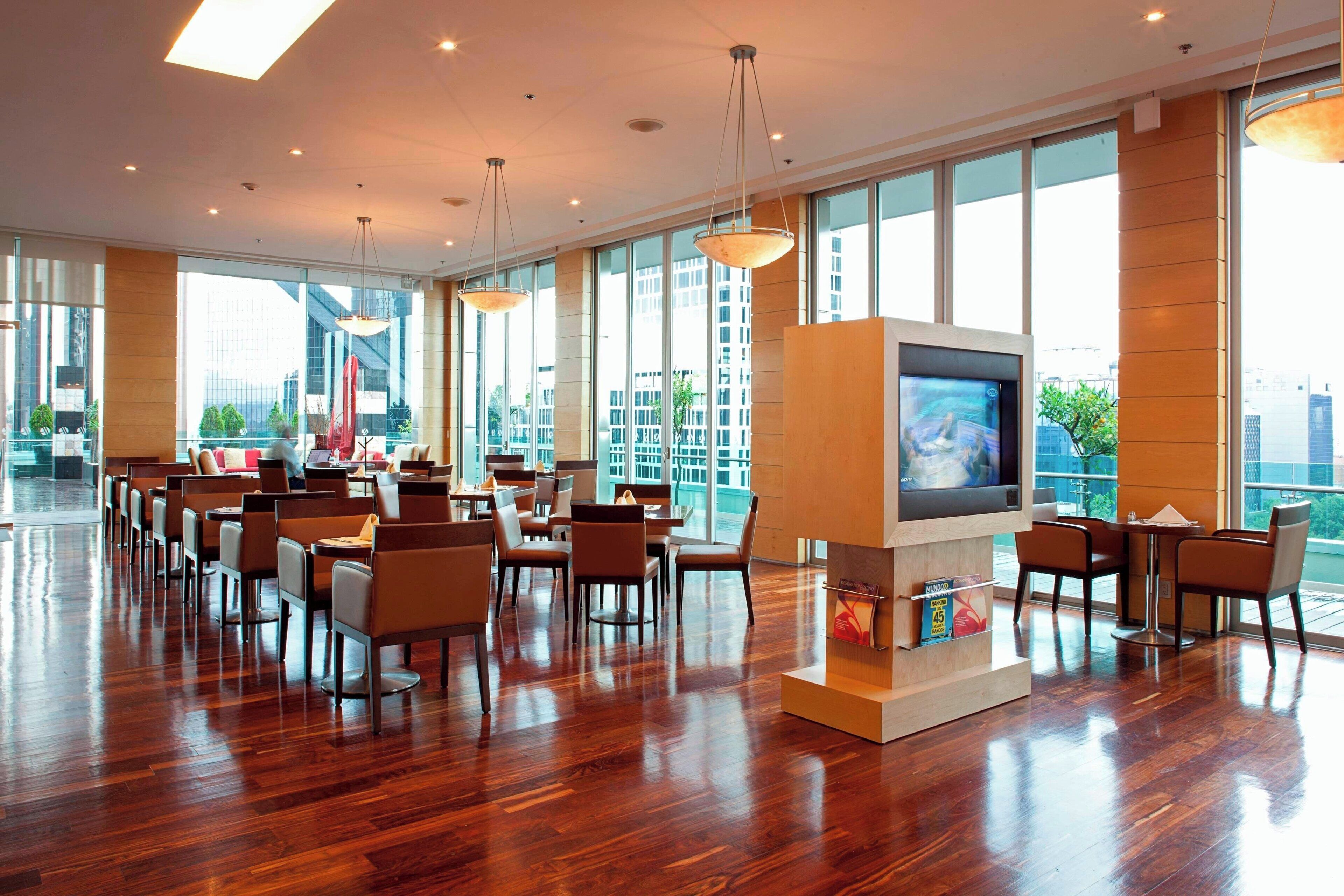 A spacious dining area with wooden flooring, large windows, and modern furniture.