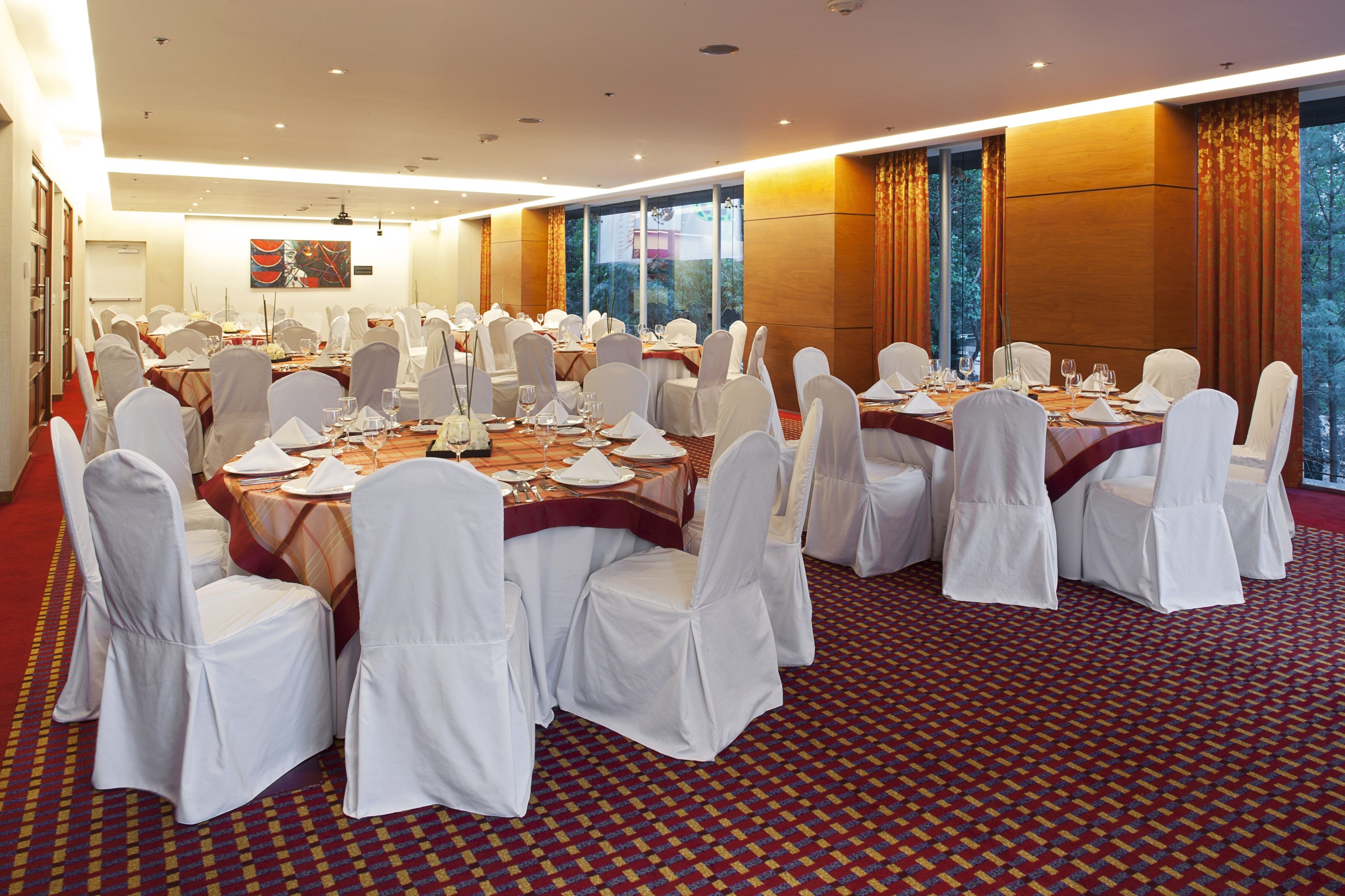 A conference room with round tables, white chairs, and a patterned carpet.