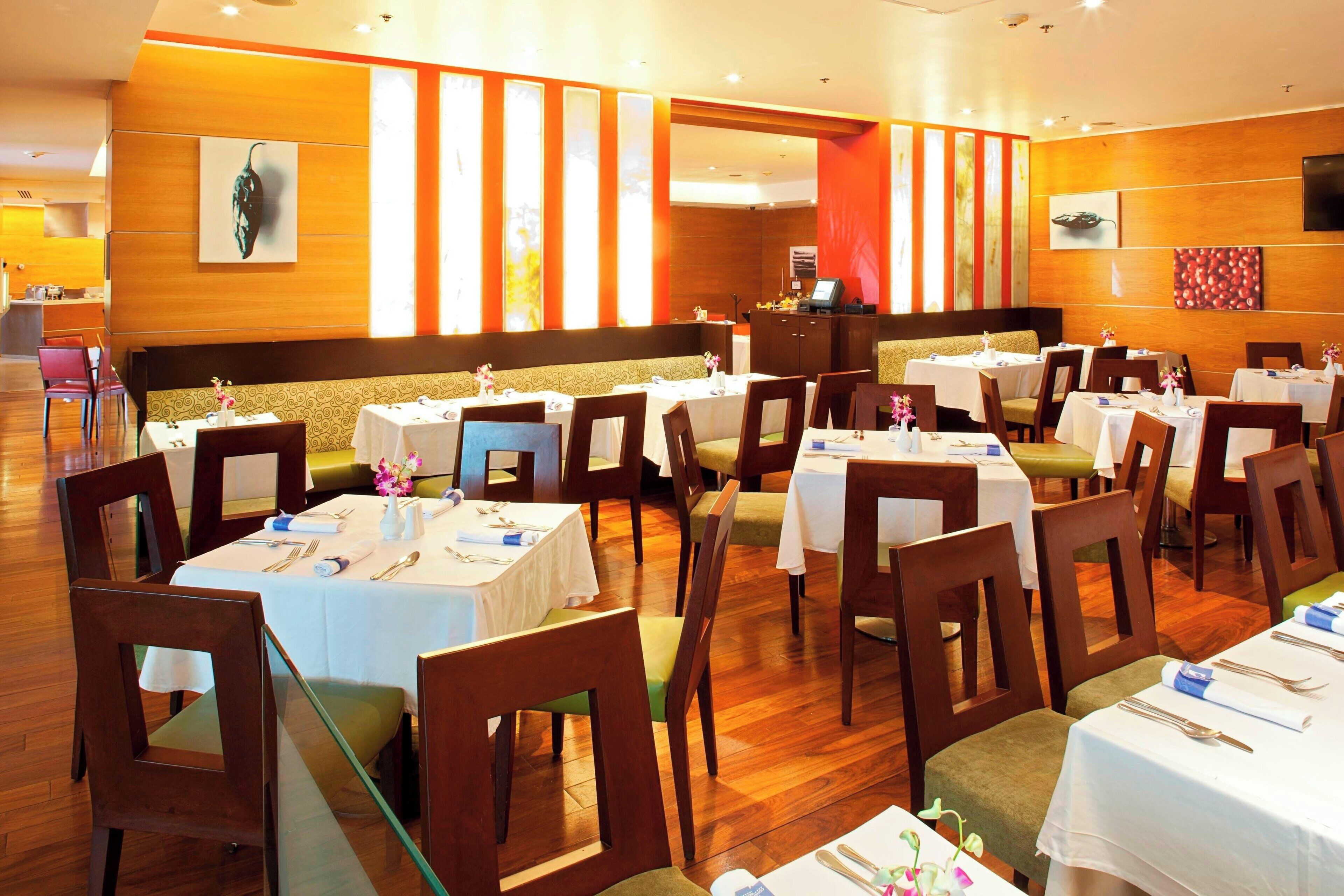 A restaurant with multiple tables and chairs, wooden paneling on the walls, and artwork displayed.