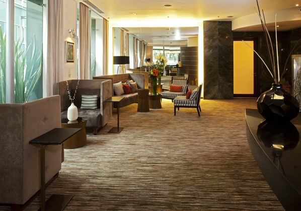 A spacious lobby with a plush seating area, a coffee table, and a decorative vase.