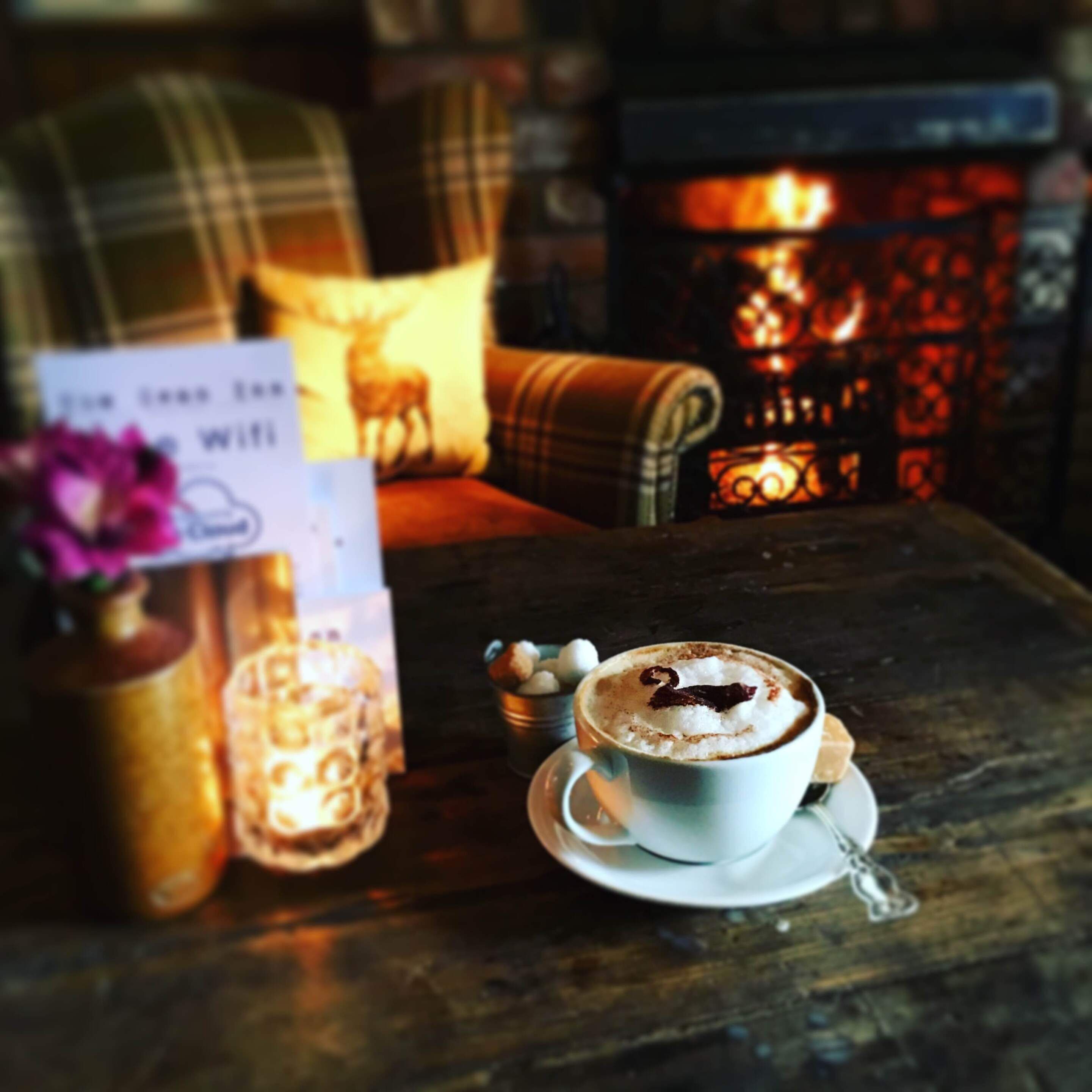 Un espace intérieur chaleureux, avec une tasse de café, une bougie et un panneau indiquant la présence d’une connexion Wi-Fi.