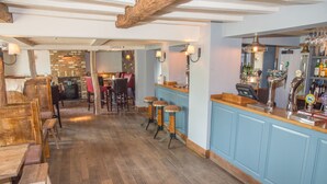 A bar area with wooden stools, a counter, and a brick wall in the background. - The Swan Inn (Worcester)