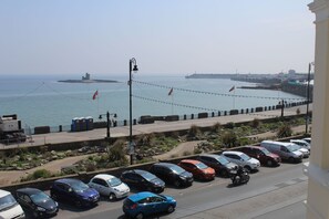 Una carretera costera con coches aparcados y vistas al mar.