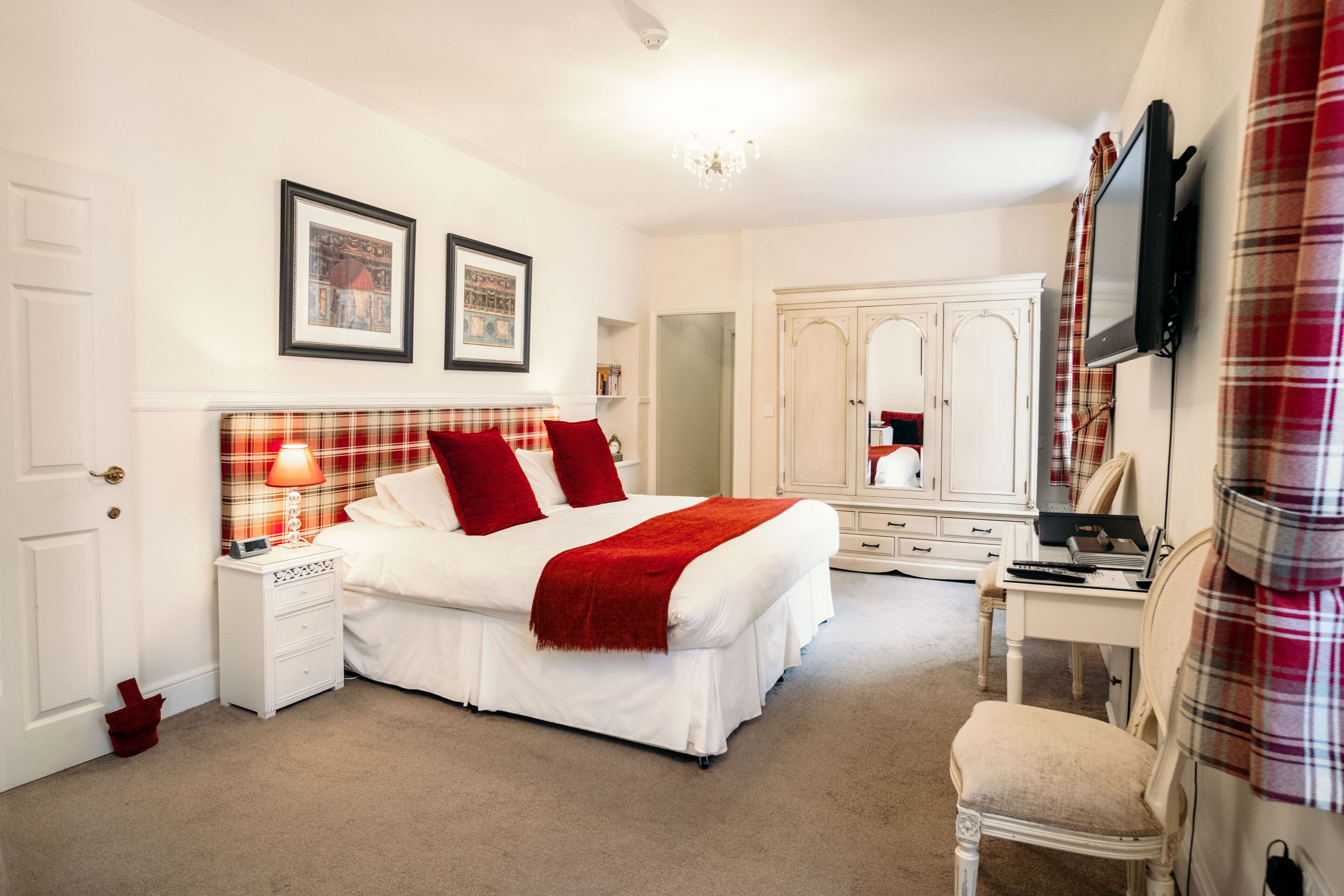 Une chambre à coucher bien rangée, avec un lit, des tables de chevet, un bureau et un téléviseur.