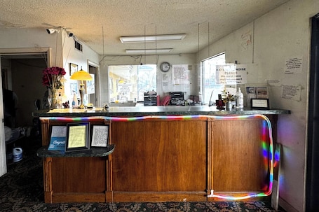 A reception desk with a wooden finish, a clock on the wall, and various informational posters.. Super Value Inn Richland Near Americus US 280