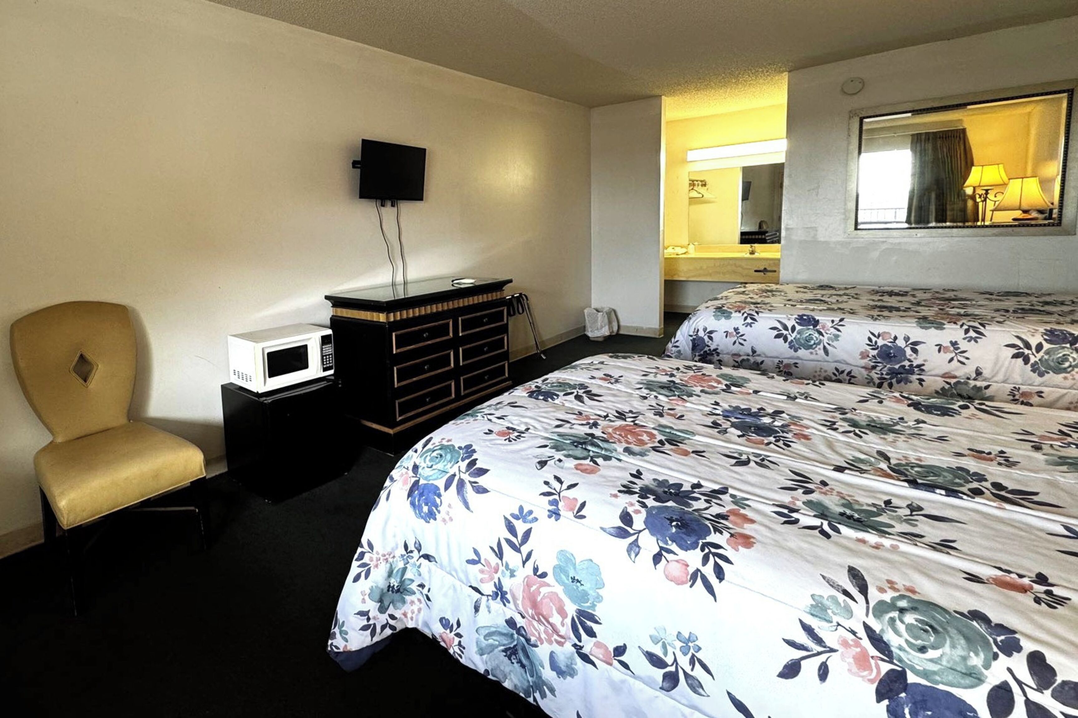 Une chambre d’hôtel avec deux lits, une télévision, un four à micro-ondes, une commode et une chaise.