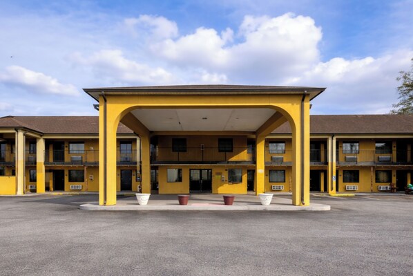 A yellow motel with a covered entrance and multiple balconies.