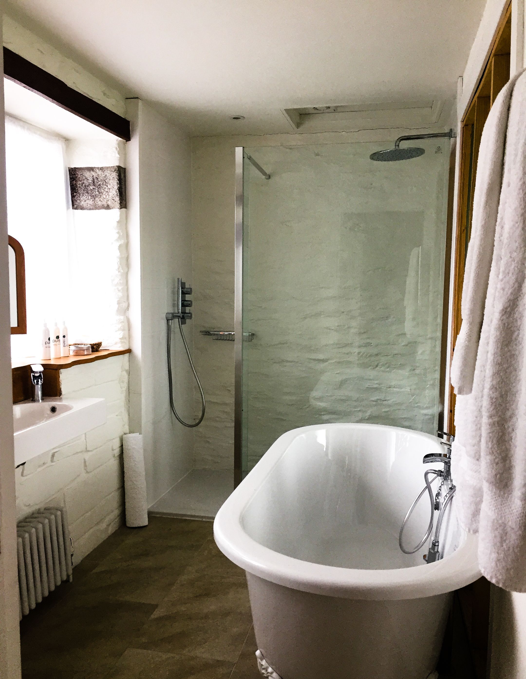 A bathroom with a freestanding bathtub, a glass shower enclosure, and a sink with a wooden countertop.
