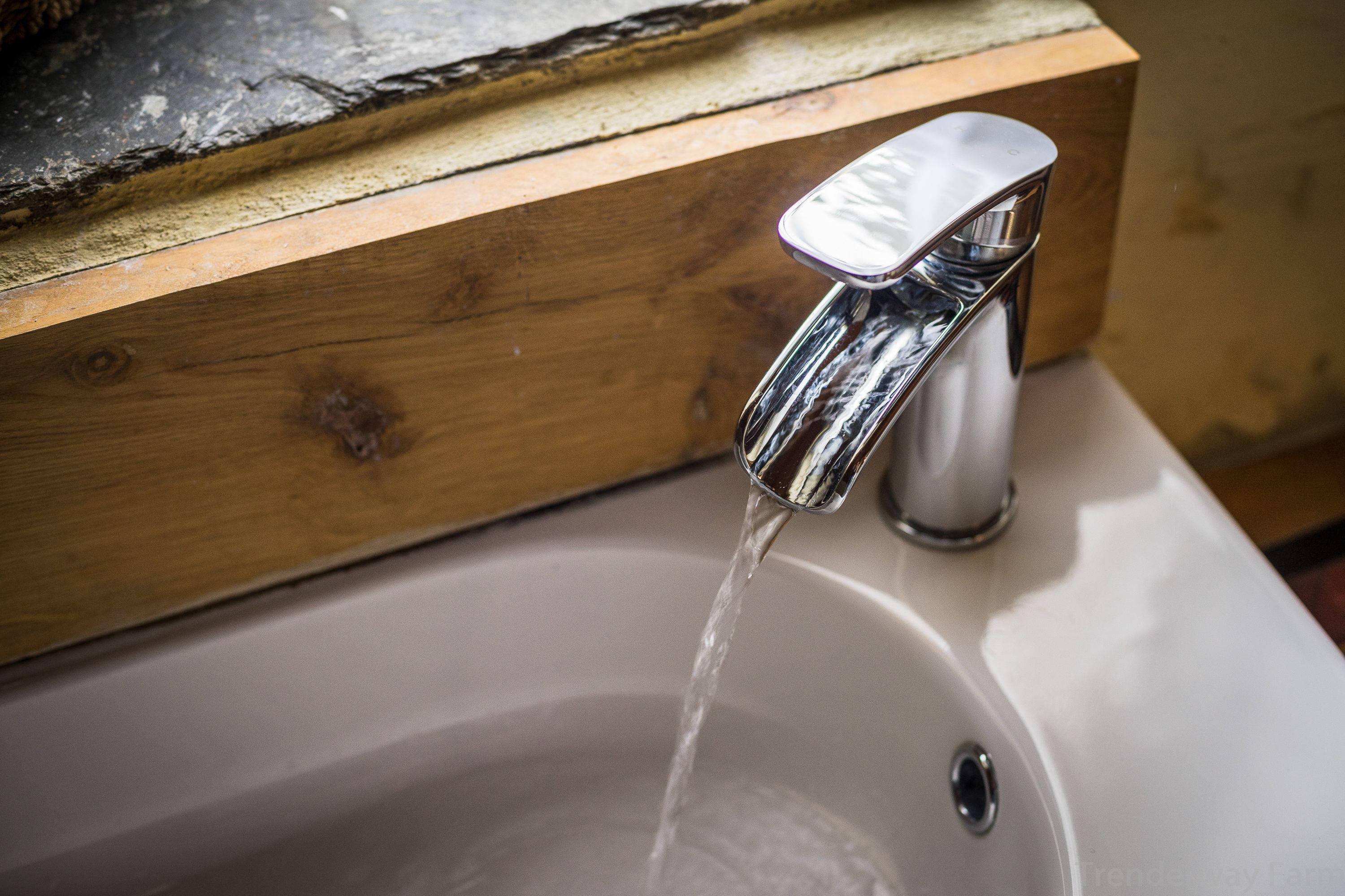 A bathroom sink with a chrome faucet and wooden countertop.