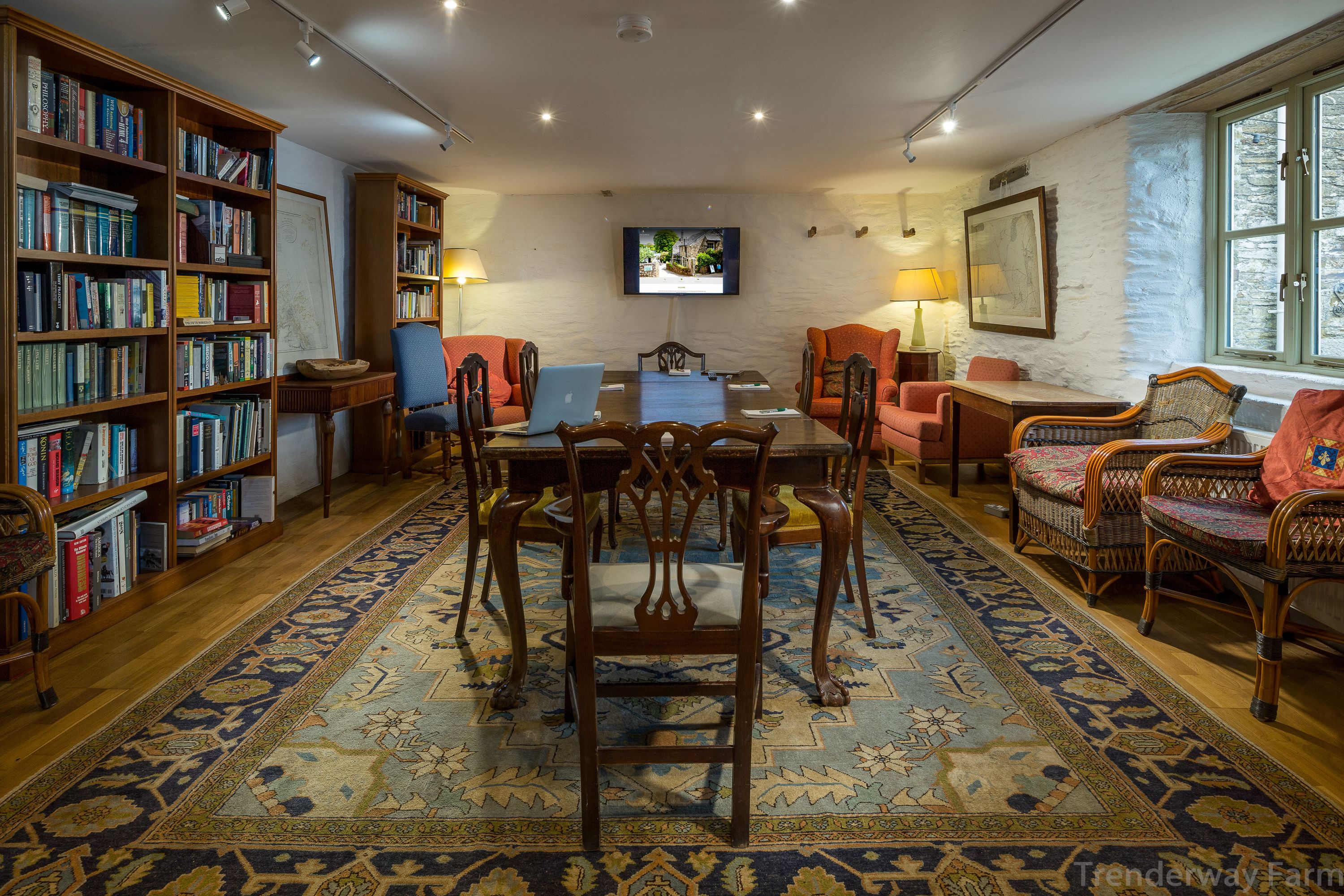Een knusse bibliotheek met boekenkasten, een eettafel en comfortabele zitplaatsen.