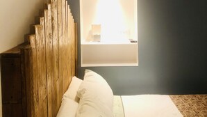 Un dormitorio con cabecera de madera, mesita de noche y lámpara de pared.