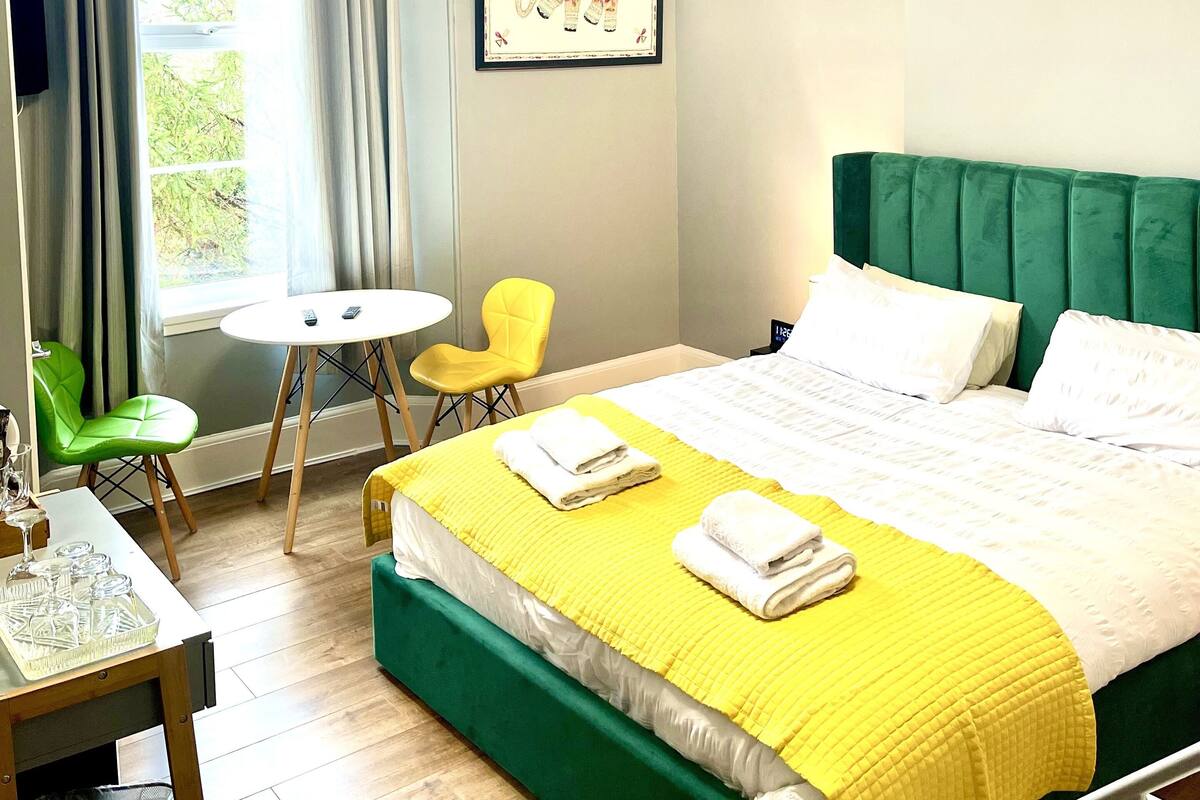 A hotel room with a bed, a desk, a chair, and a window with curtains.