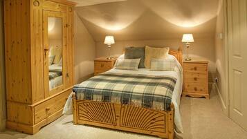 Een slaapkamer met een houten bed, twee nachtkastjes, een houten garderobe en een spiegel.