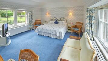 A bedroom with a large bed, two bedside tables, a chair, and a view of the garden through the window.