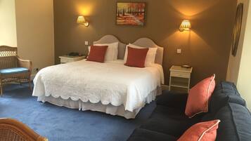 Quarto bem arrumado com uma cama grande, duas mesas de cabeceira, uma poltrona e um sofá.