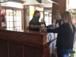 A hotel reception desk with a wooden counter and a digital display. - San Remo Palace Hotel (Villa Gesell)