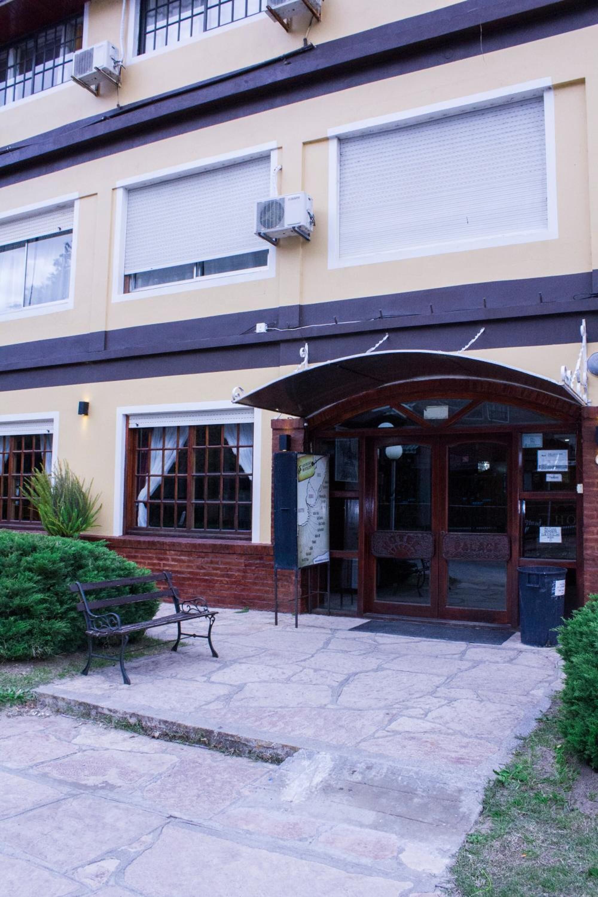 A building with a beige facade, large windows, and a wooden entrance.