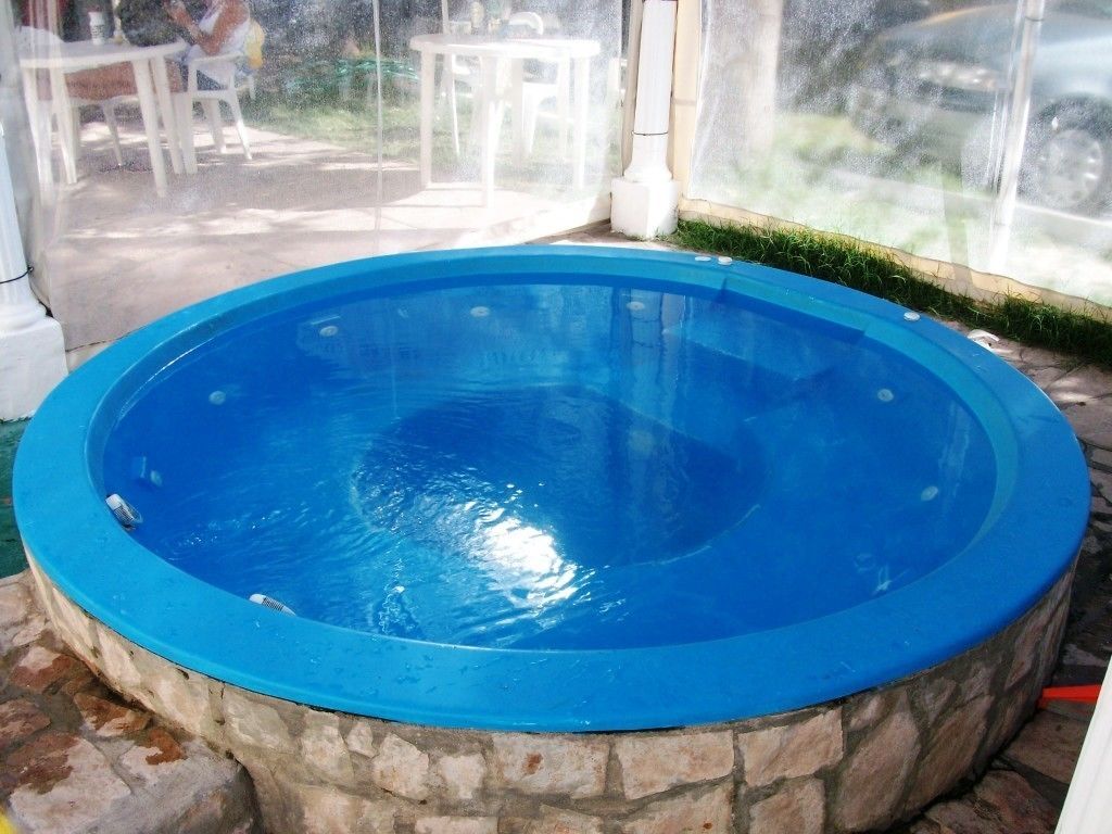 A round hot tub with a stone exterior, surrounded by a patio area with outdoor furniture.